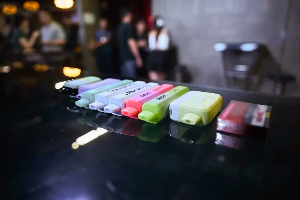 A row of colourful disposable vapes on a bar counter